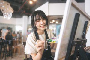 Young asian woman painting on canvas.