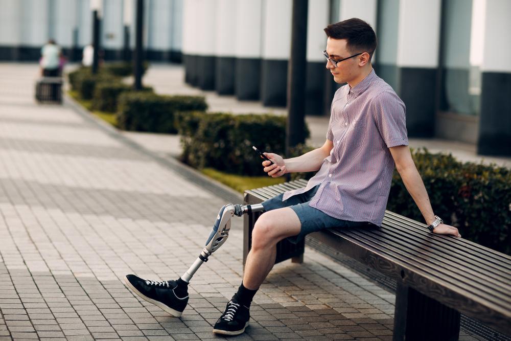 Young man with prosthetic leg looking at cell phone.