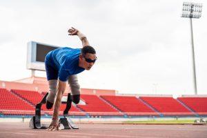 Track and field athlete amputee with artificial legs about to run.
