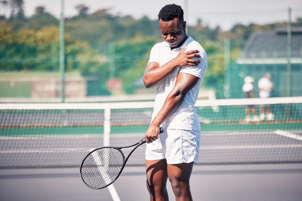 Tennis playing man holding hurt shoulder.