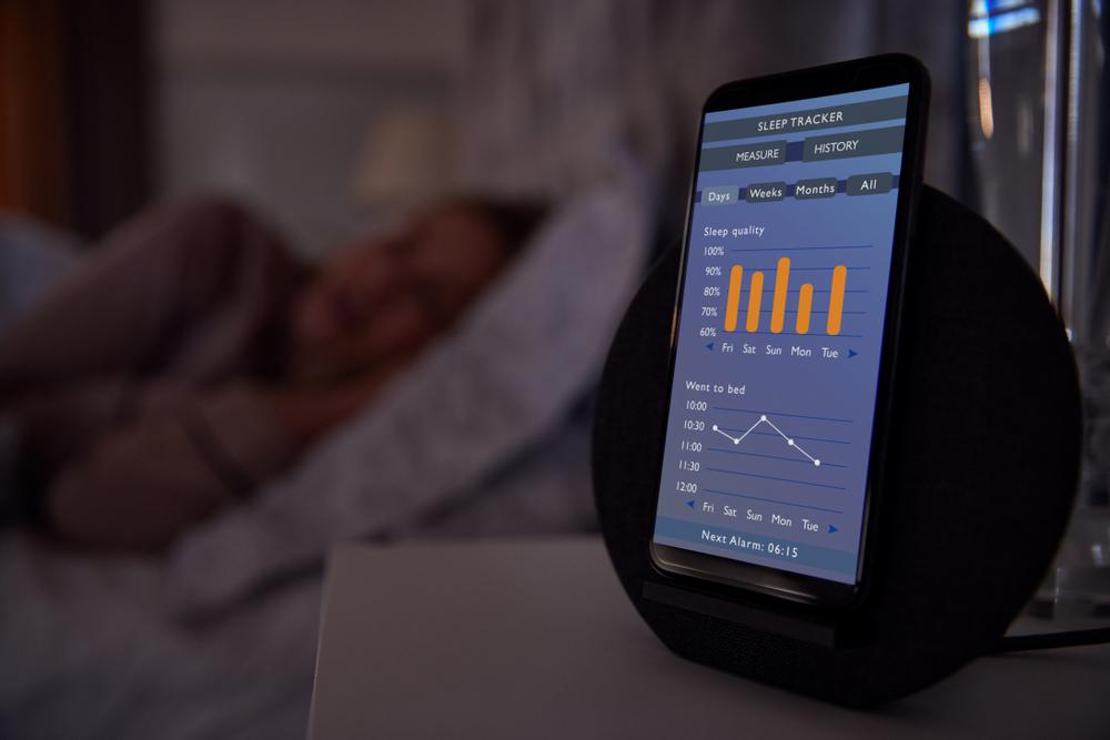Woman sleeping next to a sleep tracker app on her phone.