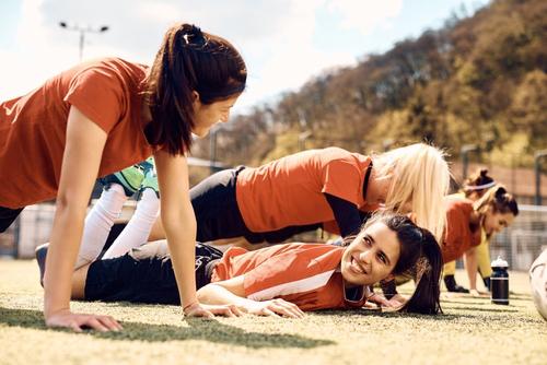 Teenage girls laughing during soccer practice.