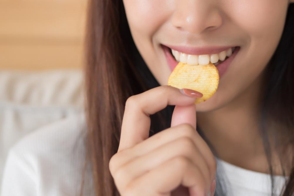 Close up of a teen girl eating a chip.