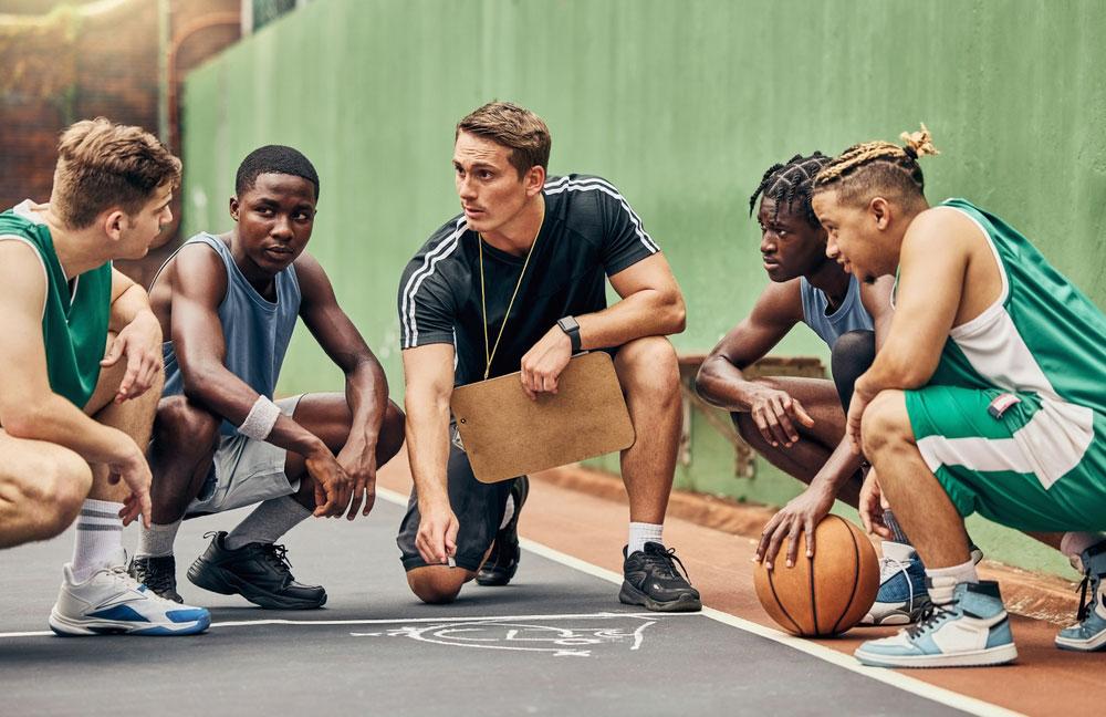 Male basketball coach in huddle with team.