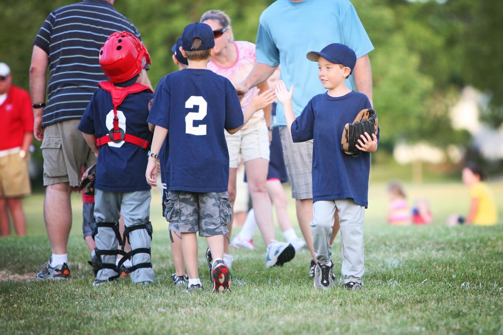 Young baseball players high fiving after game.