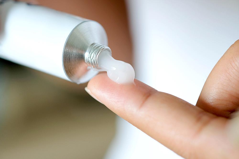 White medication squeezed out of tube onto finger.