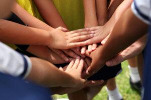 Close up of kids hand together in a huddle.