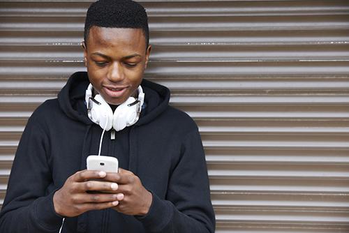 Teen boy on phone with headphones.