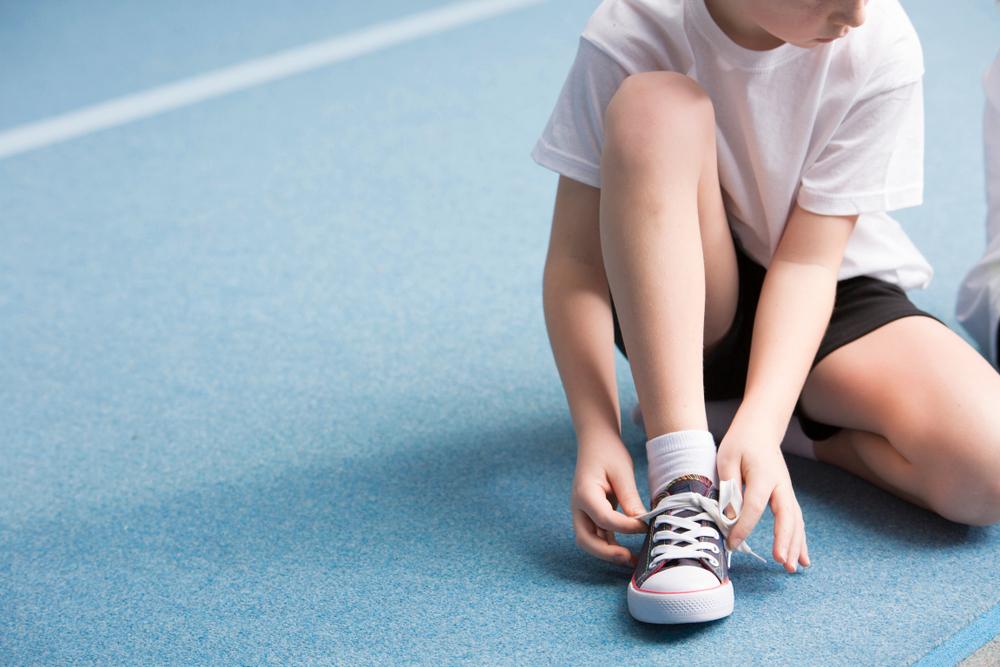 Young boy tying his shoe.