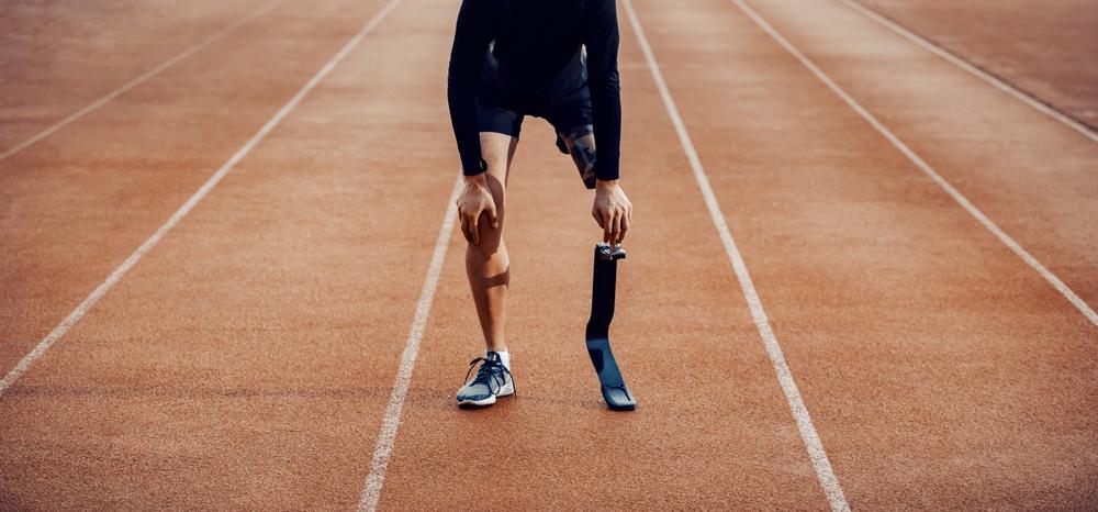 A man wearing a prosthetic leg looking tired on a track.