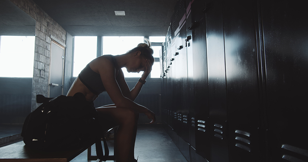 Tired female athlete in locker room alone.