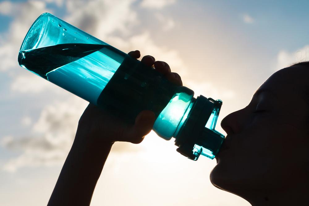 Shadowed person drinking a water bottle.