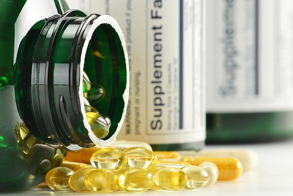 Gel cap supplements pills spilling out of a bottle.