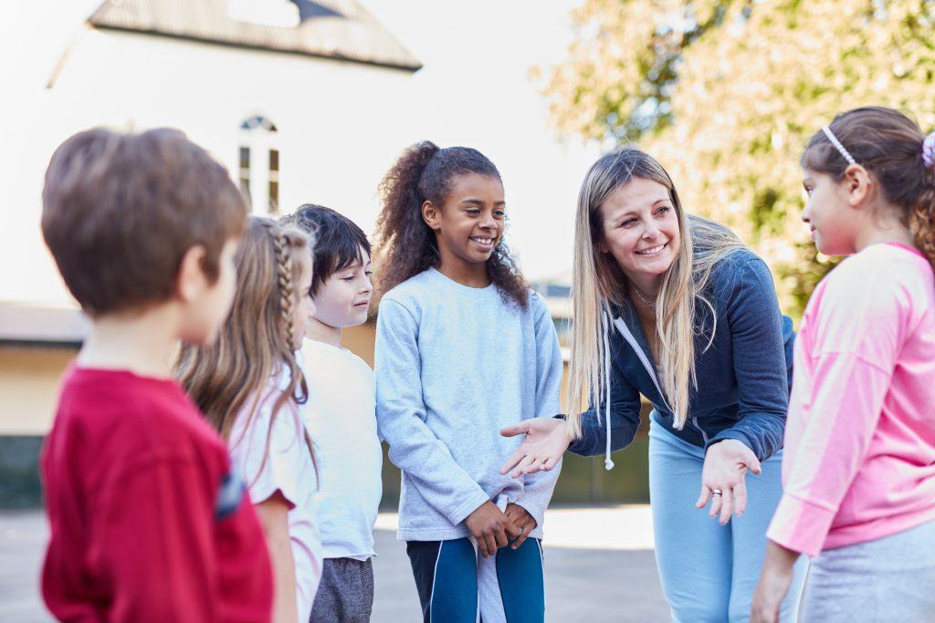 woman teaching young children outside