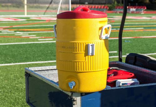 A large water cooler on a sports field.