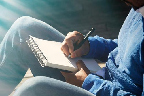 Young male writing in notebook.