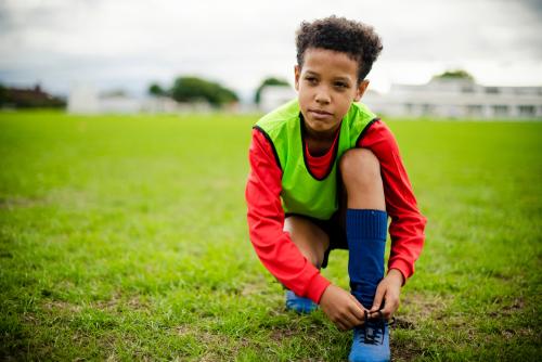 Young boy tying his shoes before soccer practice.