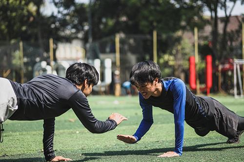 Two young men working out on a sports field.