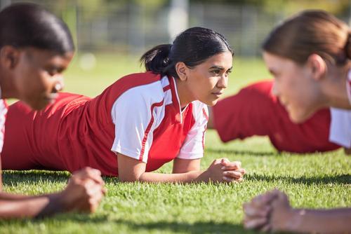 Young female soccer players stetching on the field.